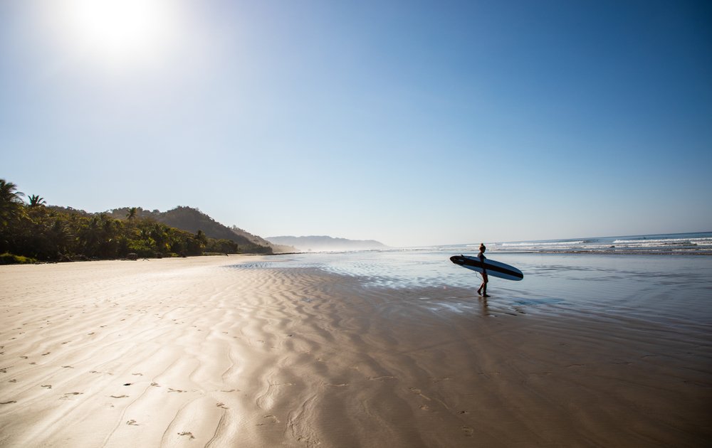 girl on beach in Costa rica holding surfboard