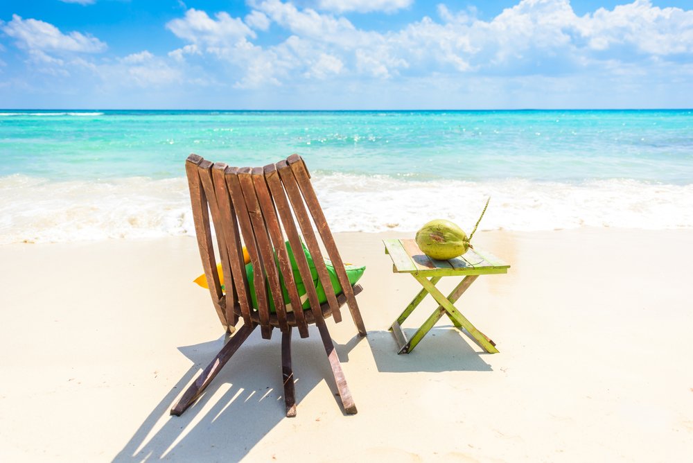 chair and a coconut on a table on the beach