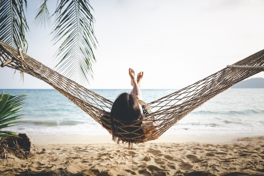 girl laying in a hammock on the beach